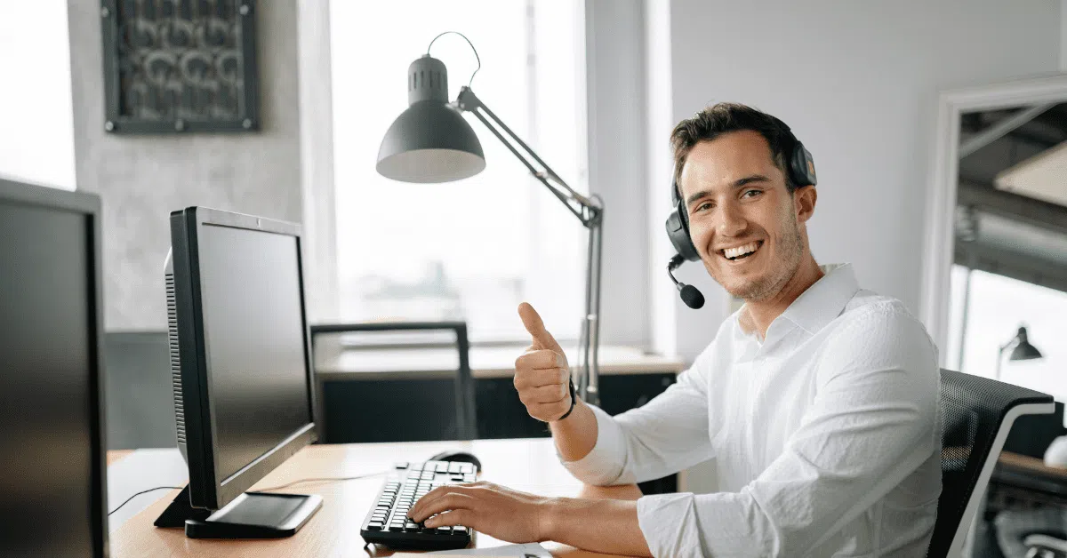 A happy IT support professional wearing a headset and giving a thumbs-up, showcasing the smooth communication of outsourced teams.